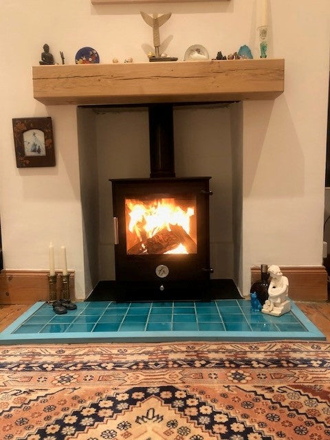 Experience the charm of the Chilli Penguin Stock Cube Wood Burning Stove paired with a stunning Turquoise Tiled Hearth and Natural Oak Deep Beam.. A perfect blend of efficiency, style, and warmth for your home.