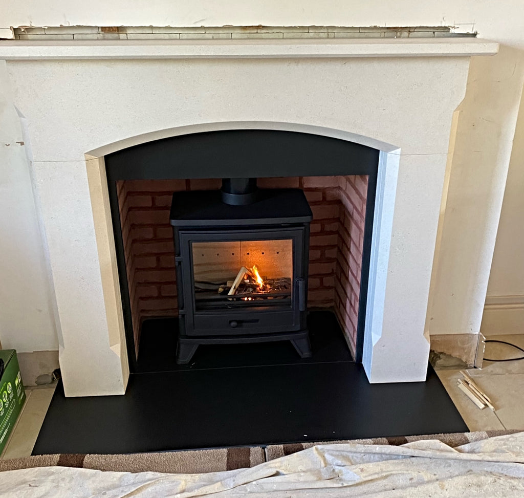 The stylish Bellingham Aegean Limestone surround features a beautiful Roman arch header with a large fireplace opening, drawing your eye down to the highly efficient Bassington Eco cast iron stove, and its large glass picture window to the roaring fire burning inside.  The tapered Standard legs base is an optioin. Slate slips and headers and brickwork chamber panels add fireplace appeal.
