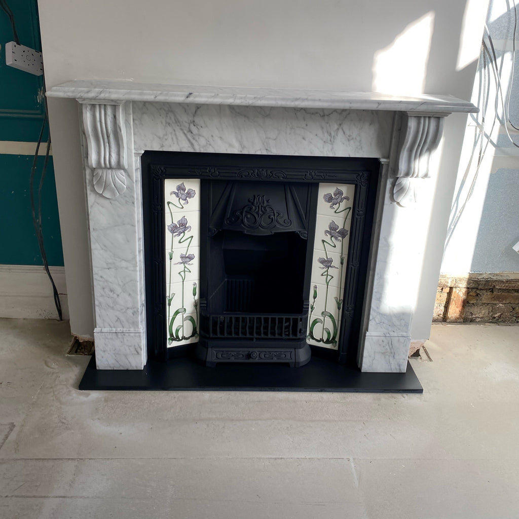 The Victoria design Nuffield Surround  in distinctive Carrara Marble and elaborate handcrafted corbels. Complimented by the  Hyebridge cast iron insertfeaturing a set of Tube Lined Lilac and Ivory Jazz Tiles and polished slate hearth.