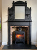 Impressive original black cast iron fireplace surround with the original ornate, black cast iron overmantle with mirror; characteristic of late Victorian or Edwardian period design, which often featured elaborate decorative elements like the scrollwork, panel designs, and urn finials seen here.