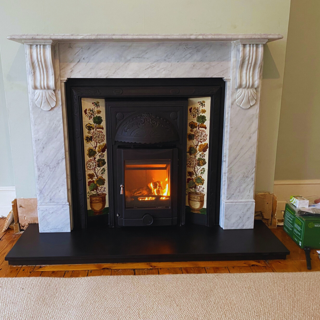 The Polaris Intrgra Ashton Cast Iron Tiled Insert Fireplace, complemented by the Nuffield, Victorian Carrara marb surround.