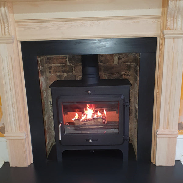 Recently installed Ekol Clarity Vision 5kW wood burning ecodesign stove featuring a wooden surround, slips and header, cleaned brickwork chamber and slate hearths. 